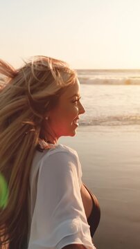 Attractive blond woman walking on the beach at sunset. Slow Motion. Vertical Video.