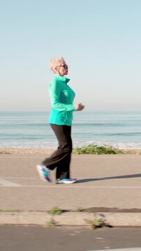 71 year old woman gets her exercise at the beach in Southern California. Vertical Video.