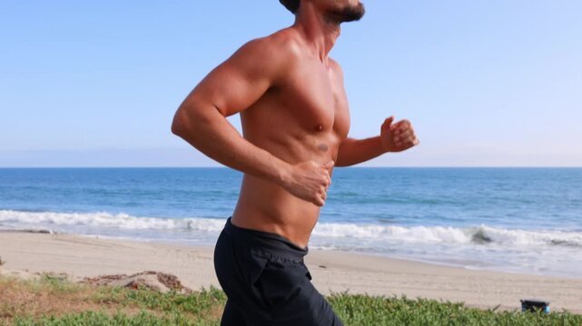 Athletic man jogging at the beach in Southern California. Slow Motion.