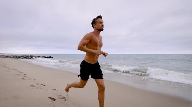 Athletic man jogging at the beach in Southern California. Slow Motion.