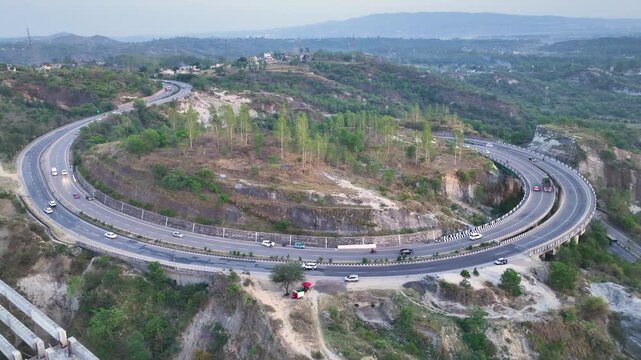 High angle view of curved unfinished highway bridge construction showing giant concrete pillars for new flyover.