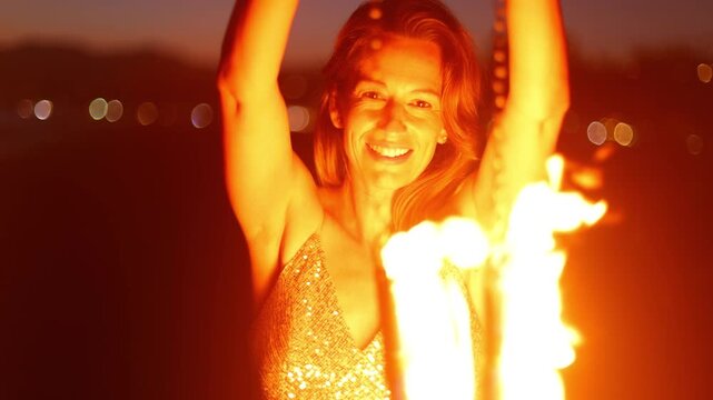 Attractive woman fire dancer spinning flames at the beach. Slow Motion.