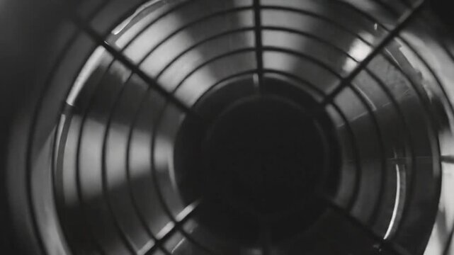 Black and white close-up of computer fan spinning and bulb illuminated inside a server case