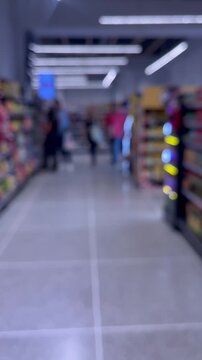POV walk through blurred supermarket aisle with shoppers in background