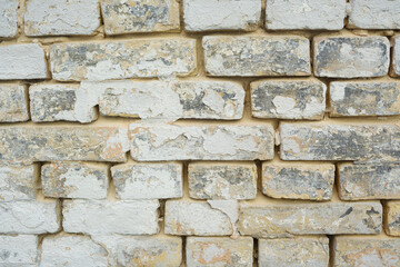 Fototapeta premium Weathered brick wall with peeling white paint, showing aged texture and rough surface detail.