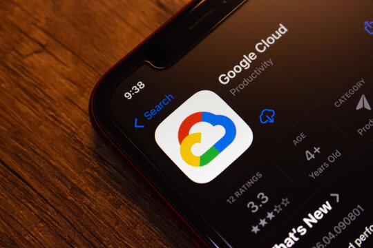 Mexico City, MEXICO - Apr 27 2026 : Low-angle close-up of an iPhone on a dark wooden table showing the Google Cloud app listing on the Apple App Store.