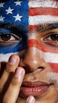 Vertical video: Closing, painted man lifting right fingers and feeling US-flag paint in front light