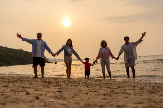 Golden Happiness: Joyful Multi-generational Family Jumping on the Beach at Sunset