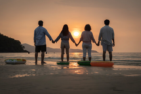 Family Bond: Happy Family Holding Hands and Watching Sunset on the Beach Together