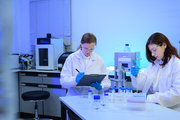 Two Female Scientists Working in Modern Research Laboratory with Equipment and Test Tubes