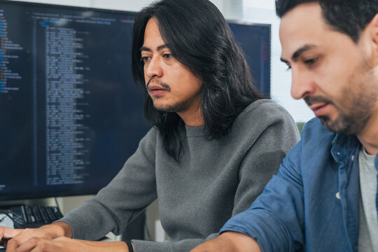 Two Serious Computer Programmers Coding on Screen Close-up Portrait of Software Engineers Writing Source Code and Developing Application Indoors
