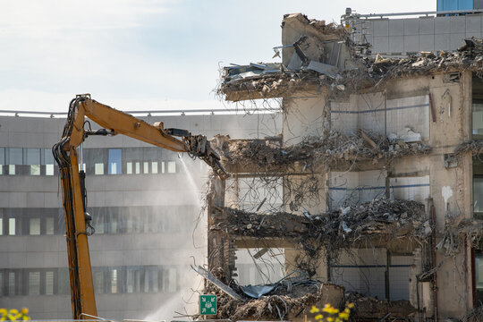 Construction site, demolition of reinforced concrete structure, gutting and renovation, hydraulic hammer dismantles building, caterpillar excavator machine