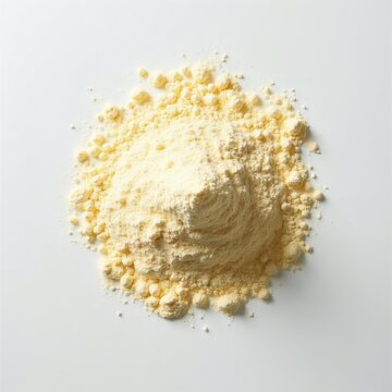 Pile of fine yellow cornstarch or arrowroot powder shown on white surface. Dry ingredient is loose, granular and light. Used in cooking and baking.