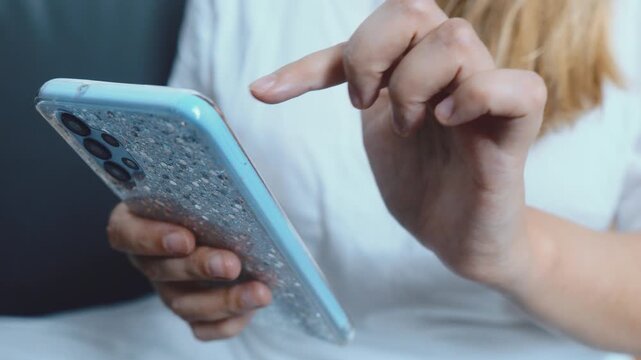 Woman's hands holding a smartphone and using a finger to tap on the touchscreen, interacting with technology and connecting online through various applications and internet services