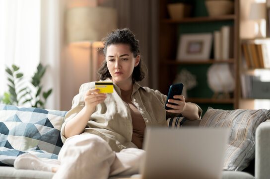 Worried Woman Shopping Online with Credit Card and Smartphone at