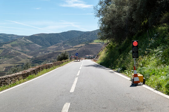 Sinaliza&ccedil;&atilde;o e condicionamento da estrada com um sem&aacute;foro numa estrada com obras ao fundo numa zona montanhosa