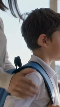Vertical video: Preparing for school mother adjusting blue backpack on boy in white polo at home