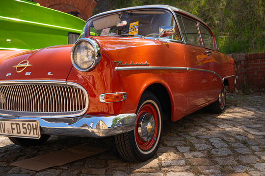 Berlin, Germany - May 2, 2026: Orange vintage Opel displayed on cobblestones