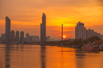 Fototapeta premium Bangkok skyline at sunset over the Chao Phraya River with a ship docked