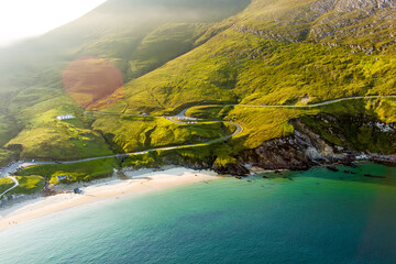 Keem Bay on Achill Island, County Mayo, Ireland, seen from above in warm evening light. This image shows the crescent beach, clear water, and steep green coastal slopes. © MNStudio