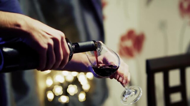 Waiter Pouring Red Wine From Bottle Into Glass At Elegant  Dinner. Tasting Beverage During Romantic Event Celebration
