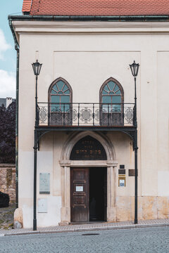 The Jewish synagogue maior in Boskovice stands at the corner of a street. It features a large wooden door and stained glass windows. People pass by and admire its design every day.