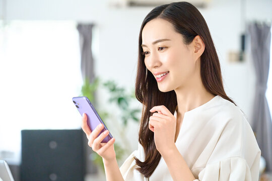 自宅でスマホを見る笑顔の女性