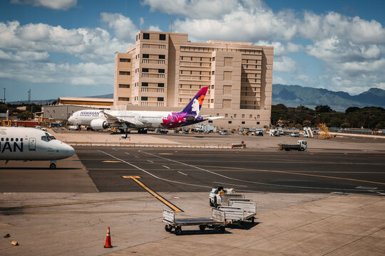Boeing 717-200 commercial aircraft  operated by Hawaiian Airlines sits parked on the tarmac at a terminal gate at Daniel K. Inouye International Airport