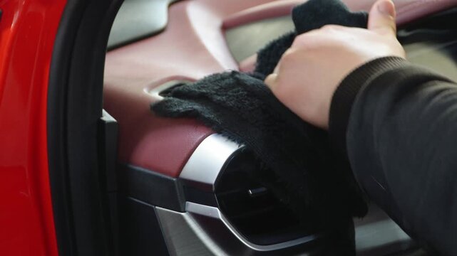 A man cleans the interior of a car using microfiber. Employees clean vehicle door professionally with microfiber for car polish. Man cleaning car interior. The detailing master clean the car interior.