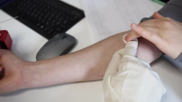 Close up blood collection procedure with syringe in medical clinic showing nurse taking blood sample from patient arm during routine laboratory examination