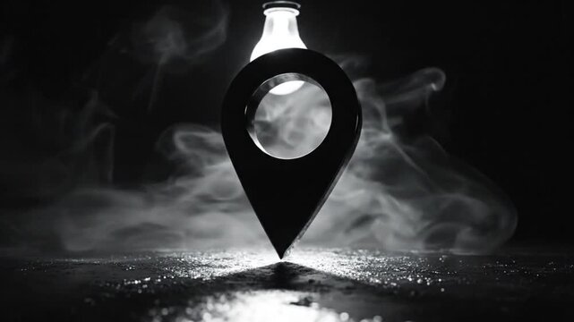 Black and white close up of a floating location pin with atmospheric smoke and a bright light bulb