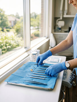 Dental assistant arranging clean instruments on a sterile tray in a bright clinic room