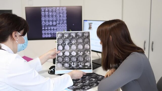 Young woman trapped in health anxiety repeatedly checks expensive medical scans in private clinic while doctor explains that test results show no serious illness and symptoms are stress related