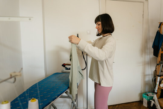 Woman ironing clothes at home on an ironing board doing laundry and household chores