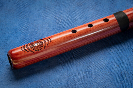native American style flute handcrafted from aromatic cedar wood against art paper