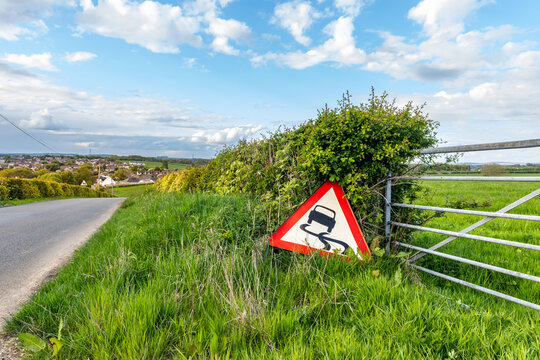 Slippery Road Warning Sign Beside Rural Country Lane in Britain