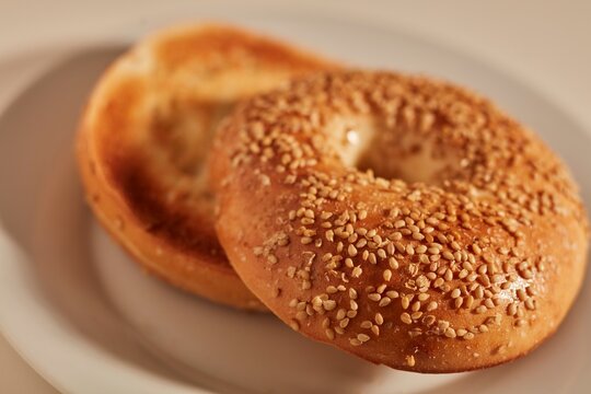 A toasted sesame bagel on a white plate.