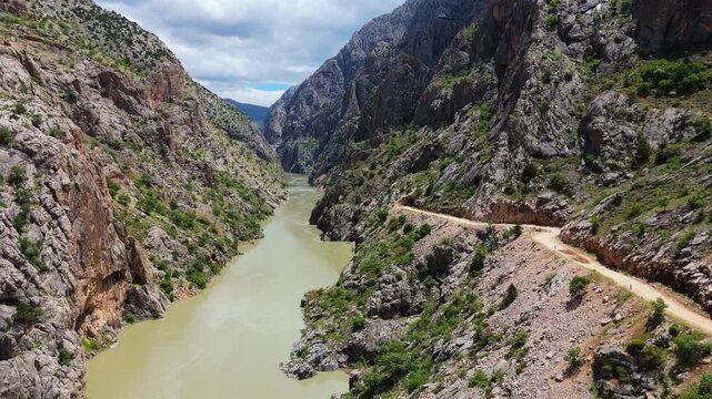 Aerial perspective flying through the deep Dark Canyon in Kemaliye, Turkey. Drone shot following the path of the Karasu River with the legendary hand-carved Stone Road visible on the cliff