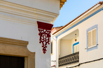 Whitewashed corner facade with red ornamental trim © Hanna Tor