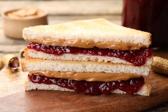 Tasty sandwiches with peanut butter, jam and nuts on table, closeup