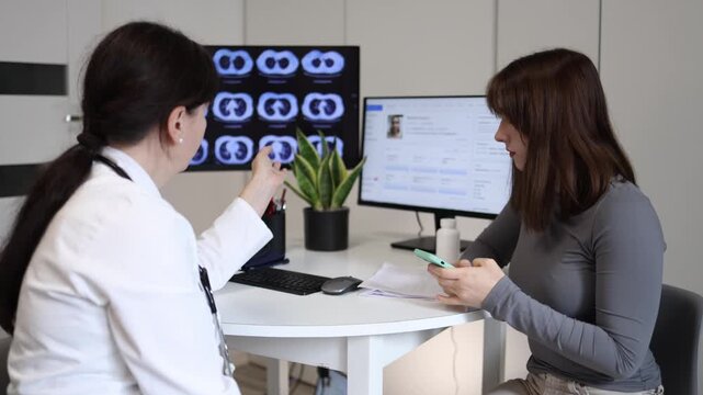 Doctor explaining important medical recommendations while young woman ignores consultation and stays focused on smartphone during clinic appointment social media addiction and digital distraction conc