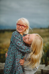 Fototapeta premium Happy sisters hugging outdoors before a storm – candid family lifestyle portrait 