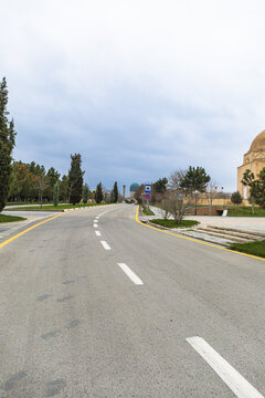 Wide-angle view of a modern asphalt road in Samarkand leading toward the blue domes of the Gur-e-Amir