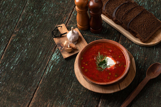 Traditional Ukrainian borscht soup with rye bread and garlic on wooden background