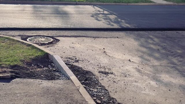 Spring highway pothole preparation empty asphalt, milled edge and loose gravel along curb under soft spring sunlight close-up