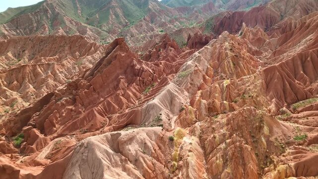 Drone weaving between towering red pinnacles and deep gullies in Skazka Canyon, Kyrgyzstan