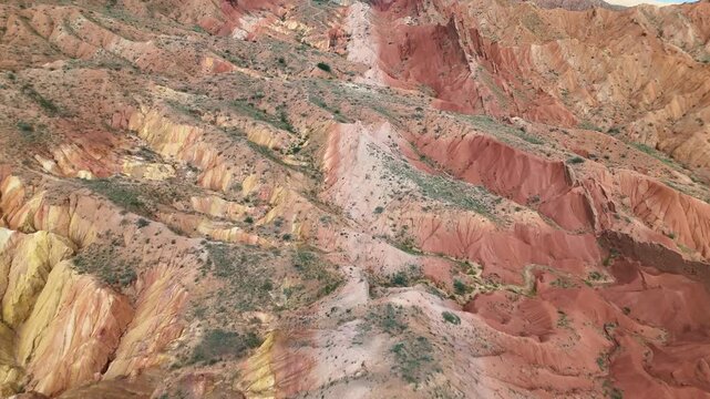 Aerial close-up of deeply eroded red and yellow rock formations in Skazka Canyon, Kyrgyzstan