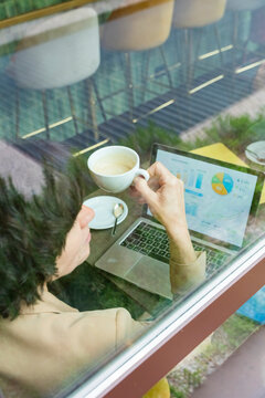 Business woman analyzing data on laptop in city cafe