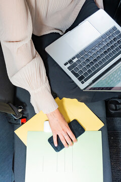 Business woman working on laptop in car with documents