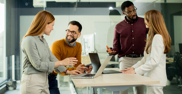Group of people discussing ideas and working on laptops in a modern office space